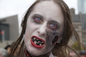 Zombie girl with purple contacts, bad teeth and a gash on one side of her face.